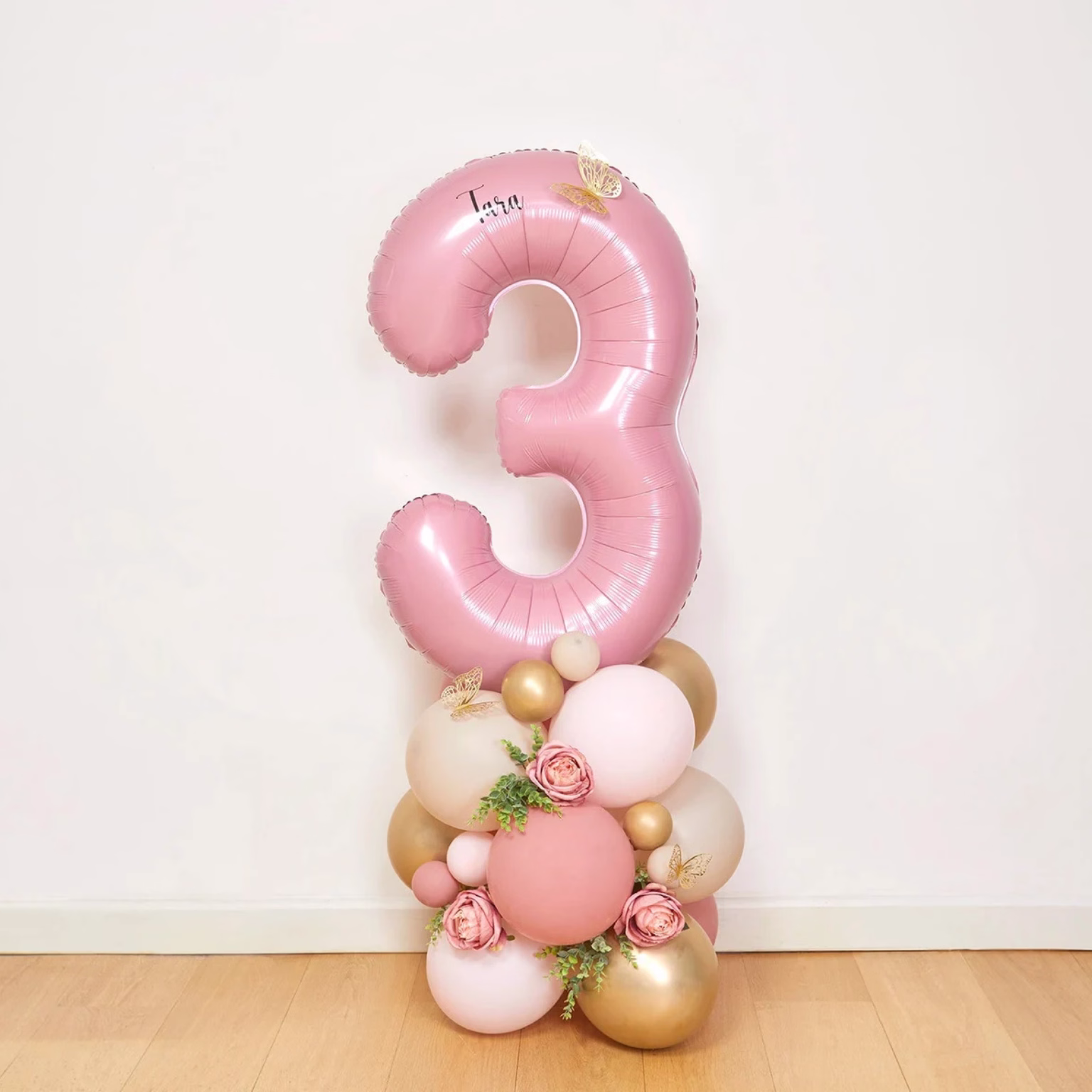 Haz que el cumpleaños de tu pequeña sea un evento mágico con esta espectacular escultura de globos para cumpleaños diseñada especialmente para niñas. Esta encantadora decoración combina un gran globo metálico rosa en forma de número, acompañado de globos en tonos rosa pastel, beige y dorado, decorados con delicadas flores rosas, follaje natural y mariposas doradas que añaden un toque de ensueño.